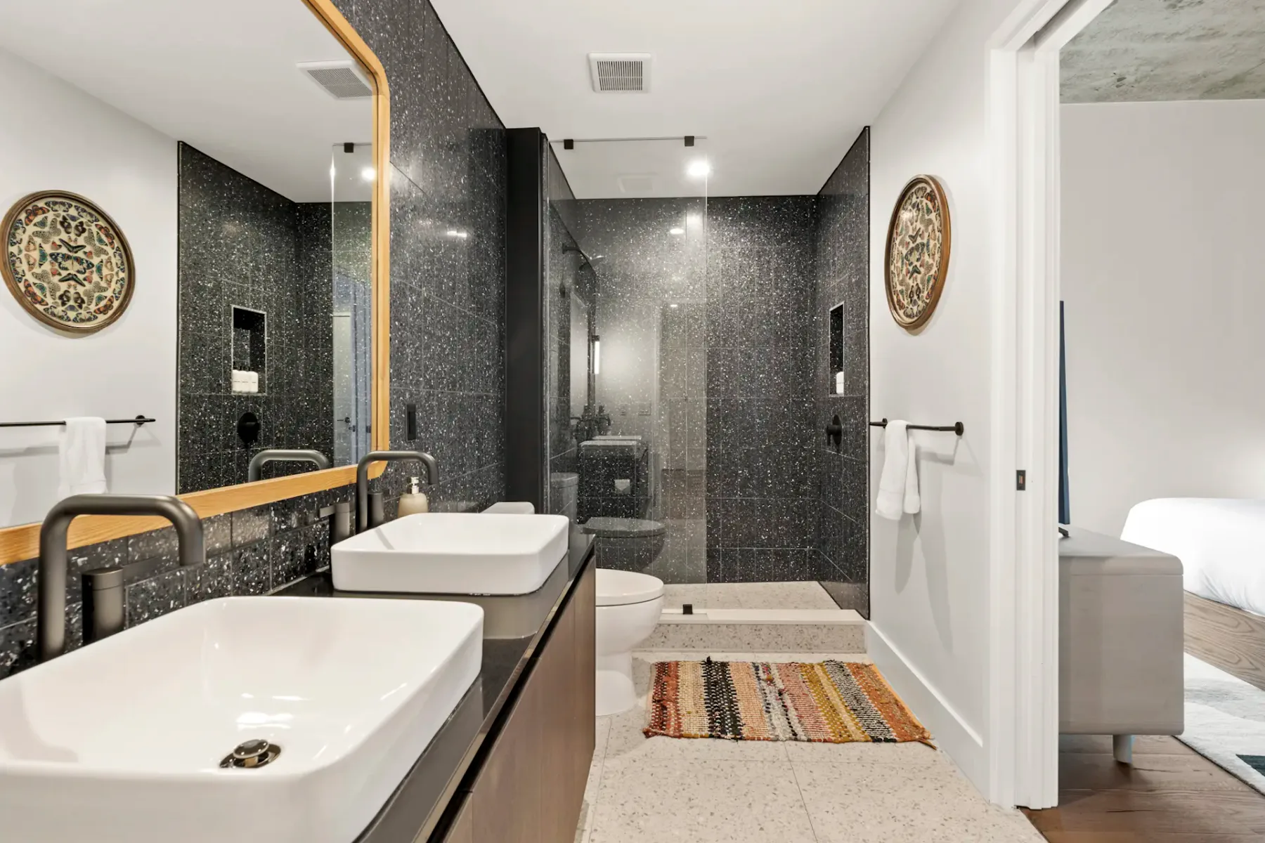 Modern bathroom with double sinks, a large mirror, and a spacious shower area.