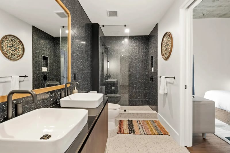 Baño moderno con dos lavabos, un espejo grande y un área de ducha espaciosa.