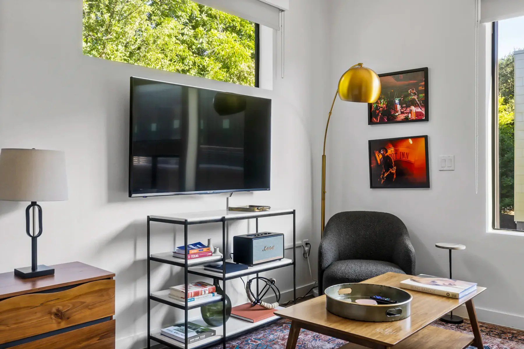 Living room with a TV, bookshelf, black chair, gold floor lamp, and wall art.