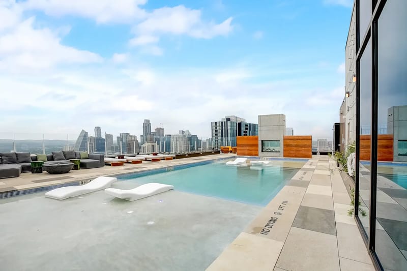 Piscina en la azotea con camastros y vistas al perfil urbano de la ciudad.
