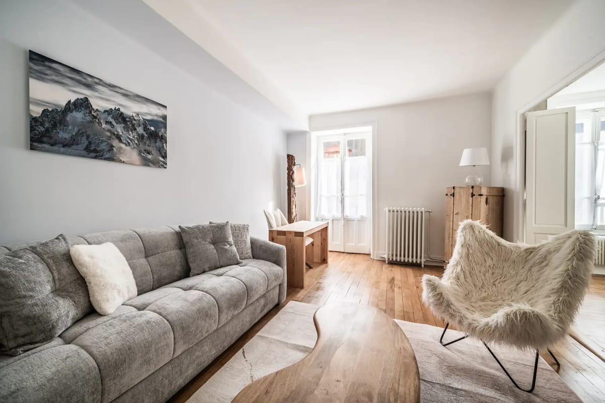 Modern living room with a gray sofa, wooden coffee table, desk, and floor lamp.