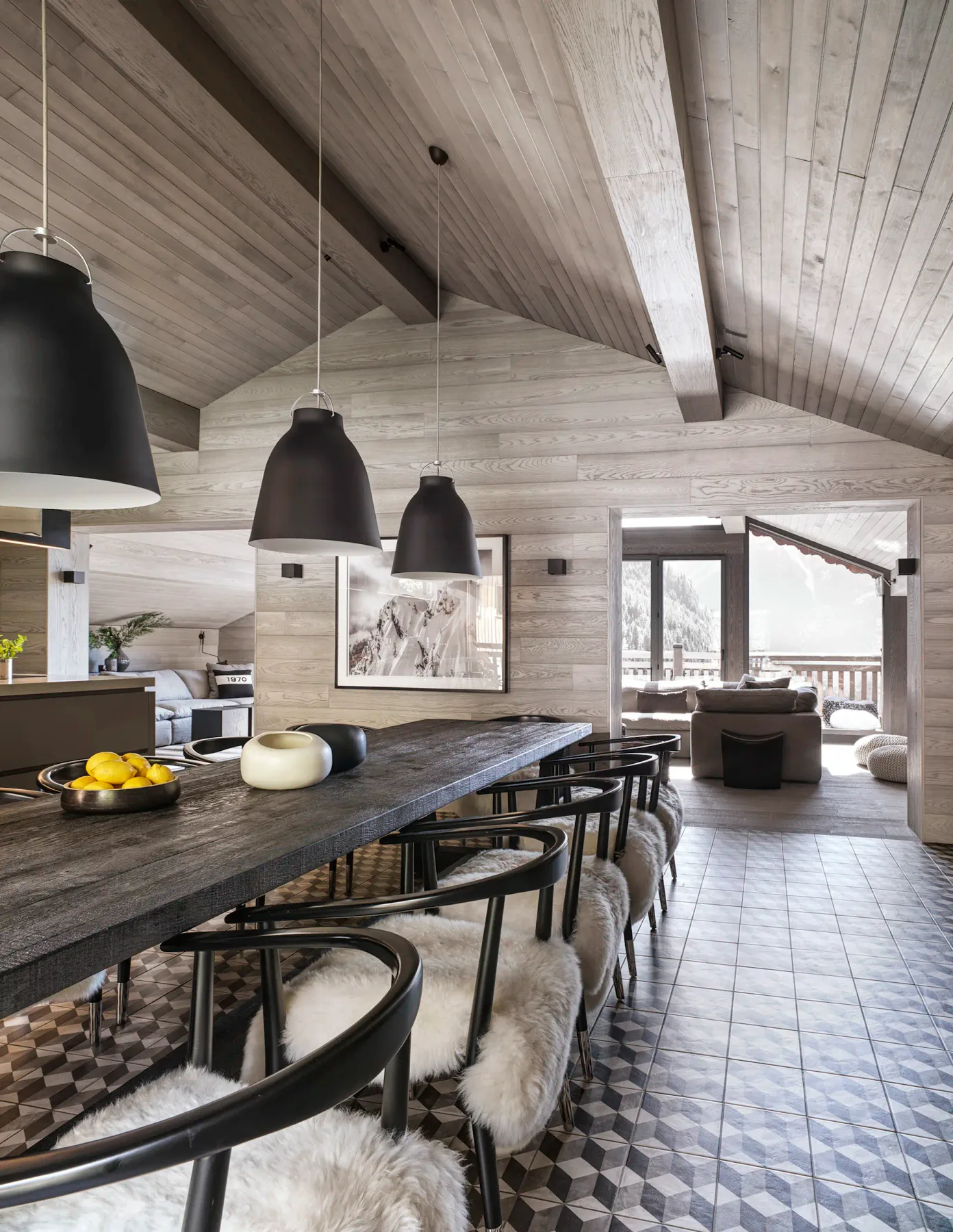 Dining area with a long table and pendant lights.