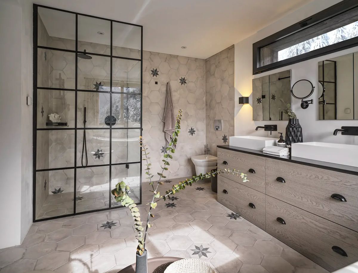 Baño con ducha con mampara de cristal y mueble de baño con dos lavabos.