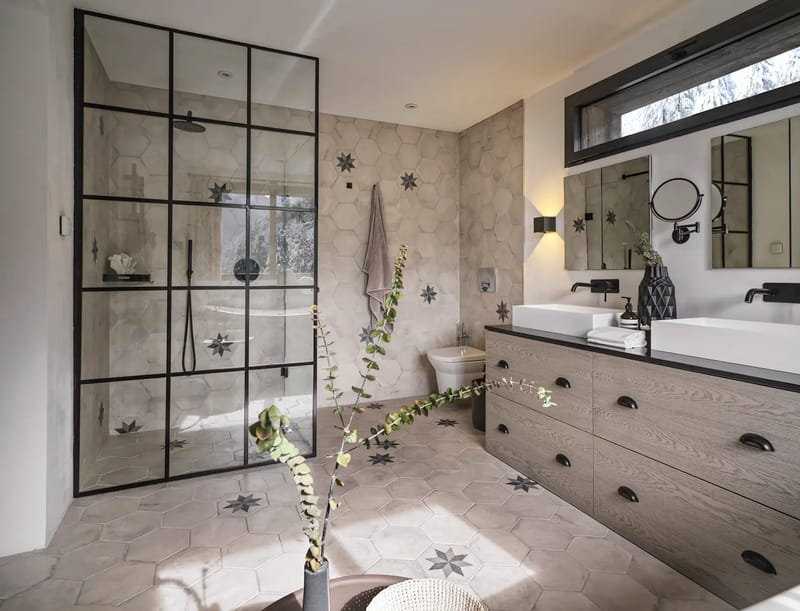 Baño con ducha con mampara de cristal y mueble de baño con dos lavabos.