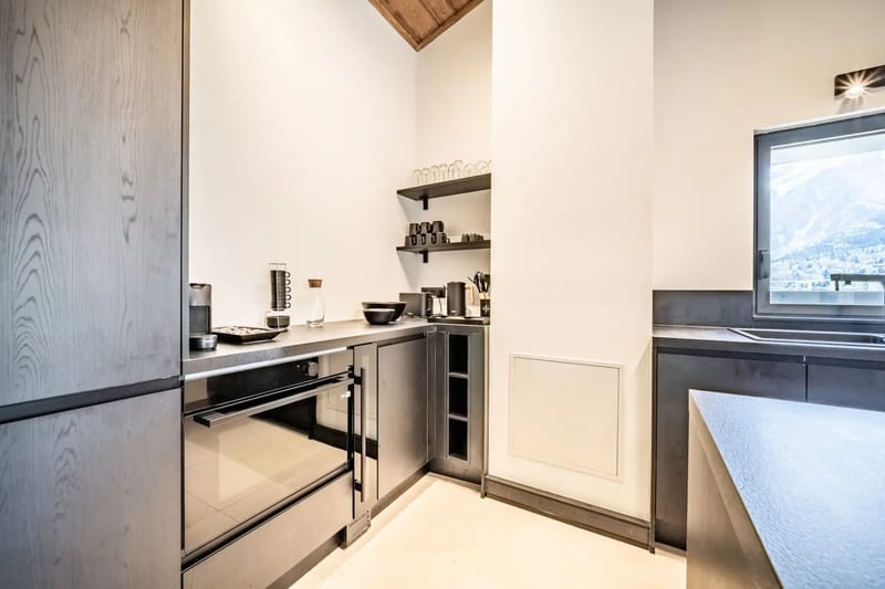 Cocina y zona de estar modernas de planta abierta, con techos de madera, grandes ventanas y una mesa de comedor.
