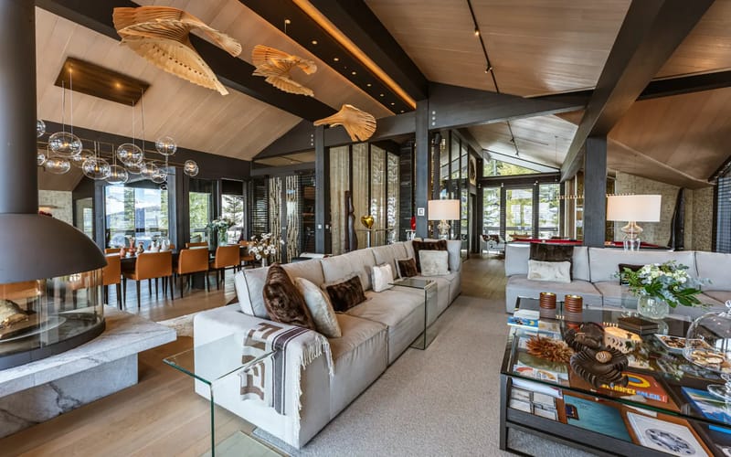 Living room with modern decor, glass walls, fireplace and dining area.