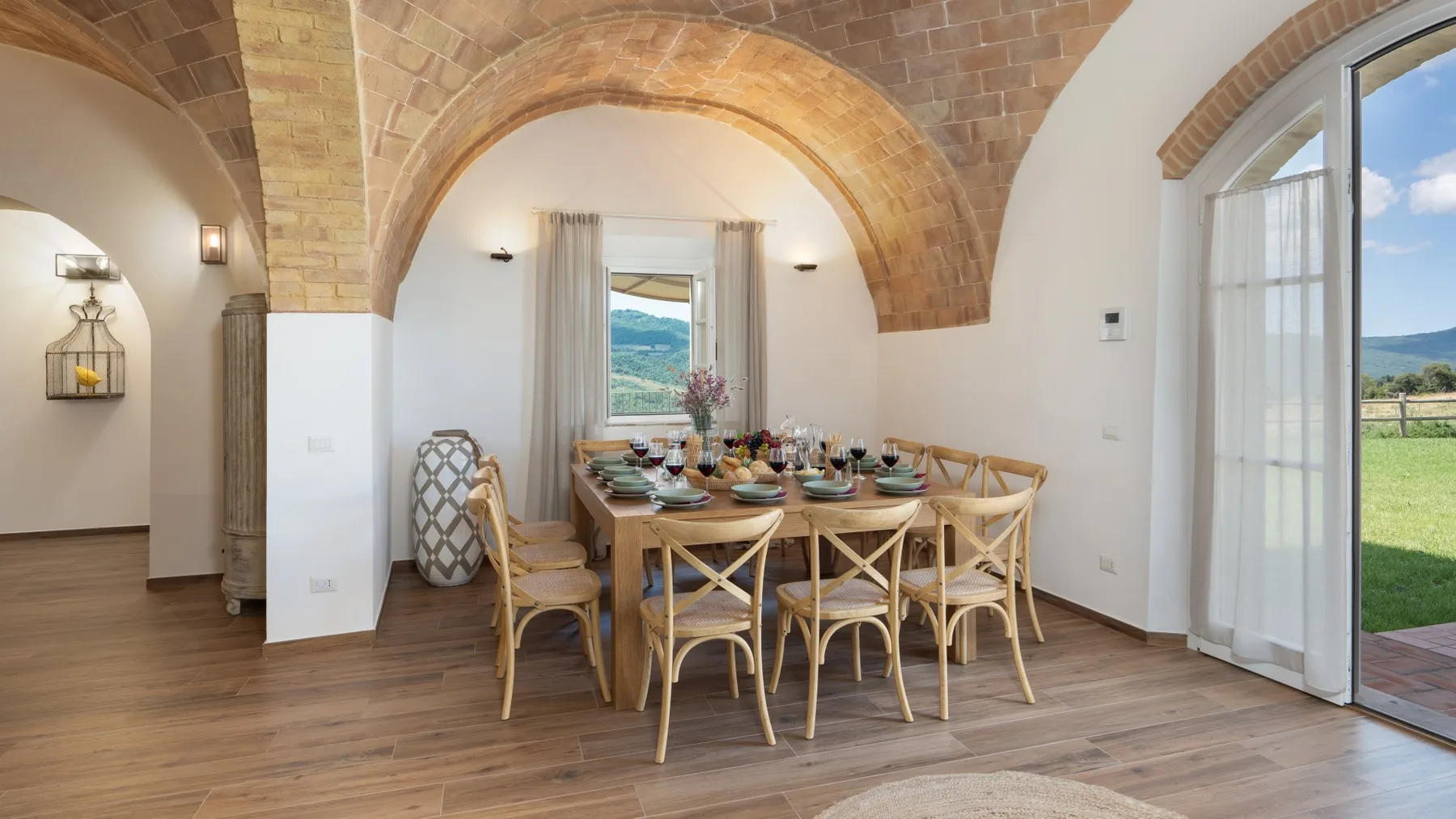 Un comedor con una mesa y sillas de madera bajo un arco de ladrillo.