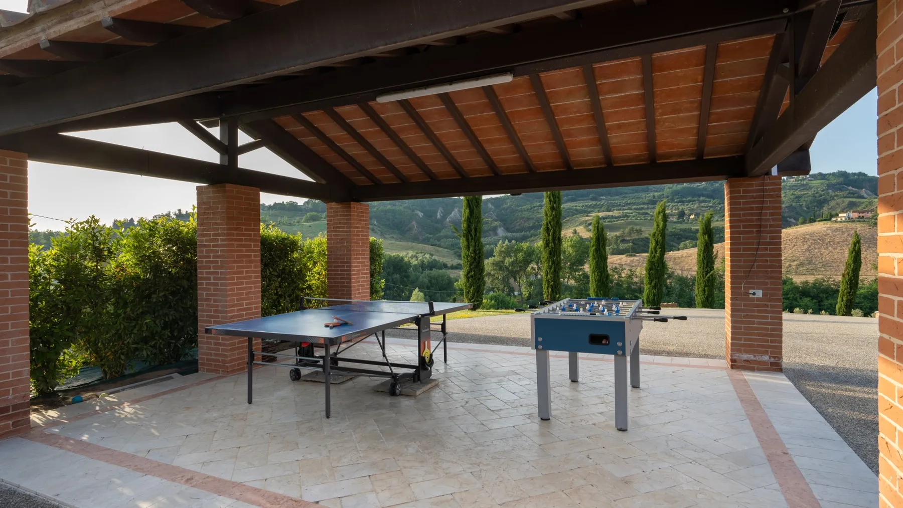 A covered outdoor recreation area with a ping-pong table and foosball table.