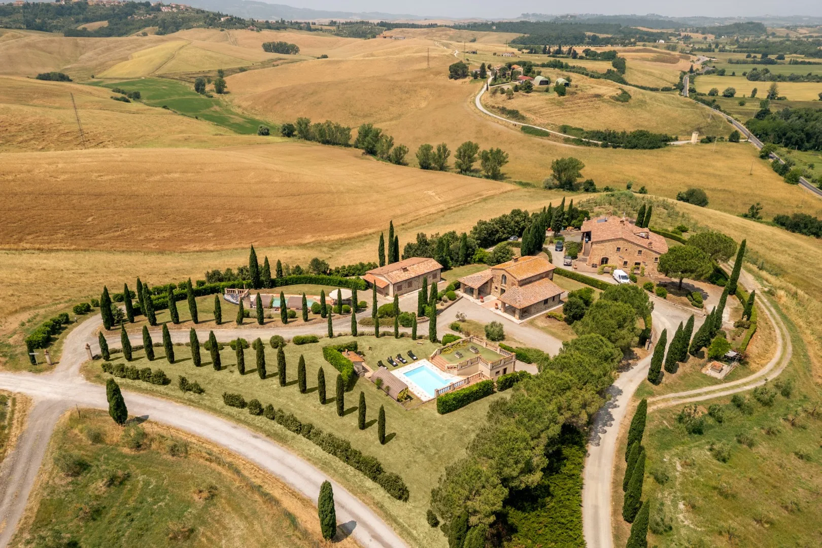Aerial view of a countryside estate with buildings, gardens, and a swimming pool.
