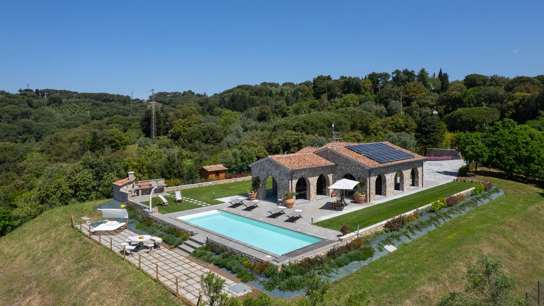 A stone building overlooks a swimming pool and landscaped grounds.