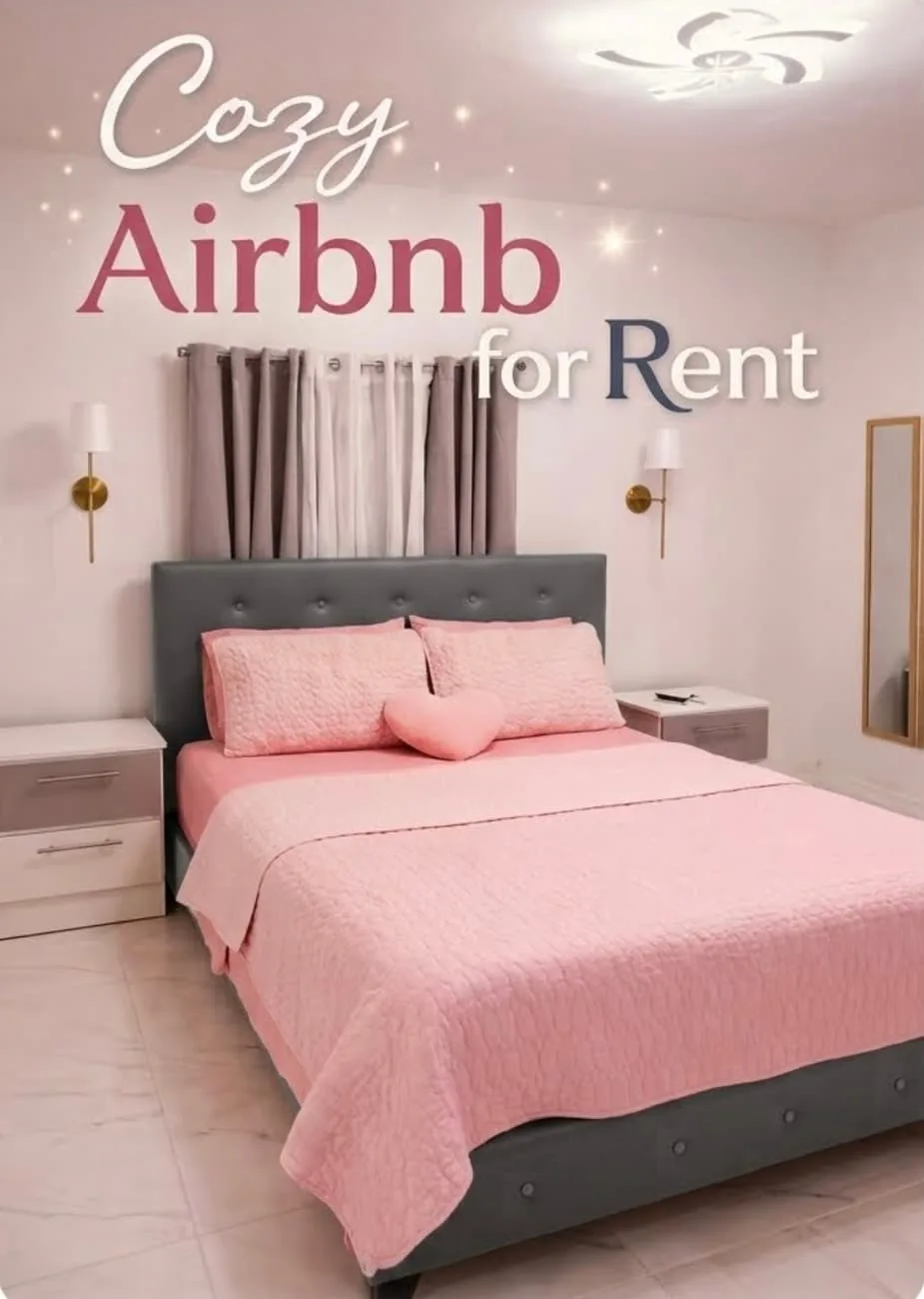 A bedroom with a pink bed, gray headboard, and curtains.