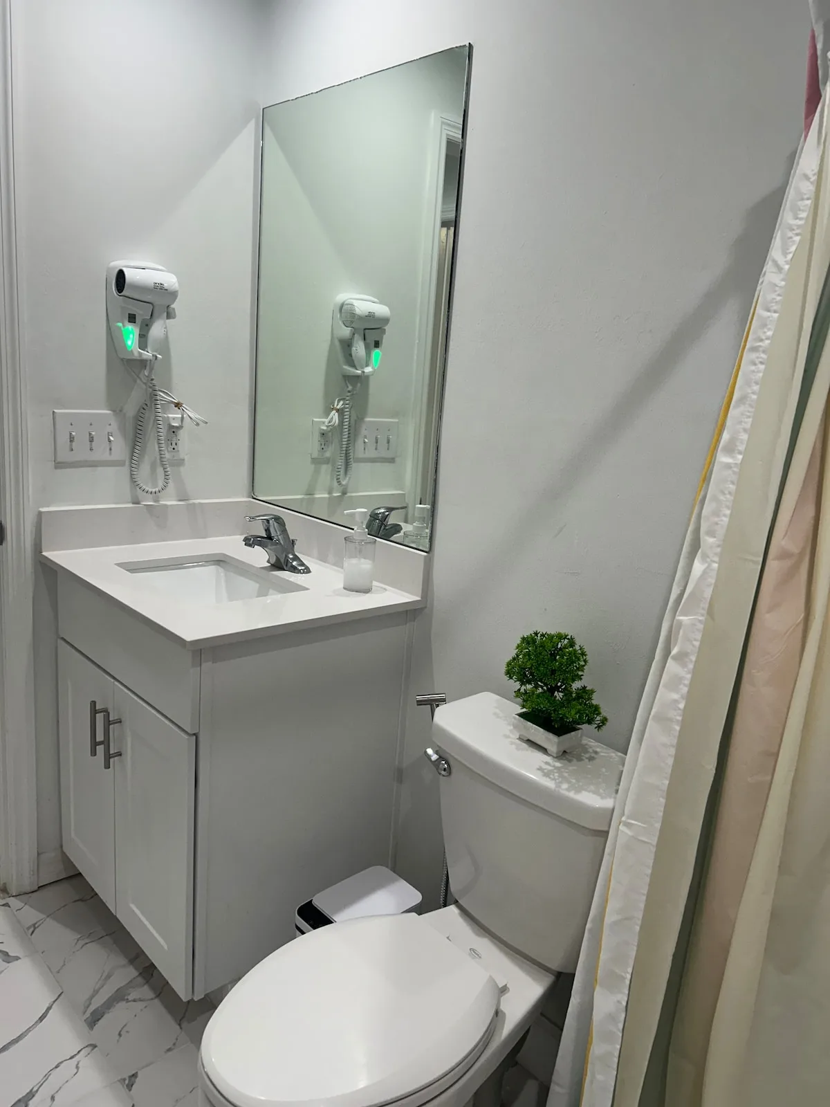 A bathroom with a sink, mirror, toilet, and shower curtain.