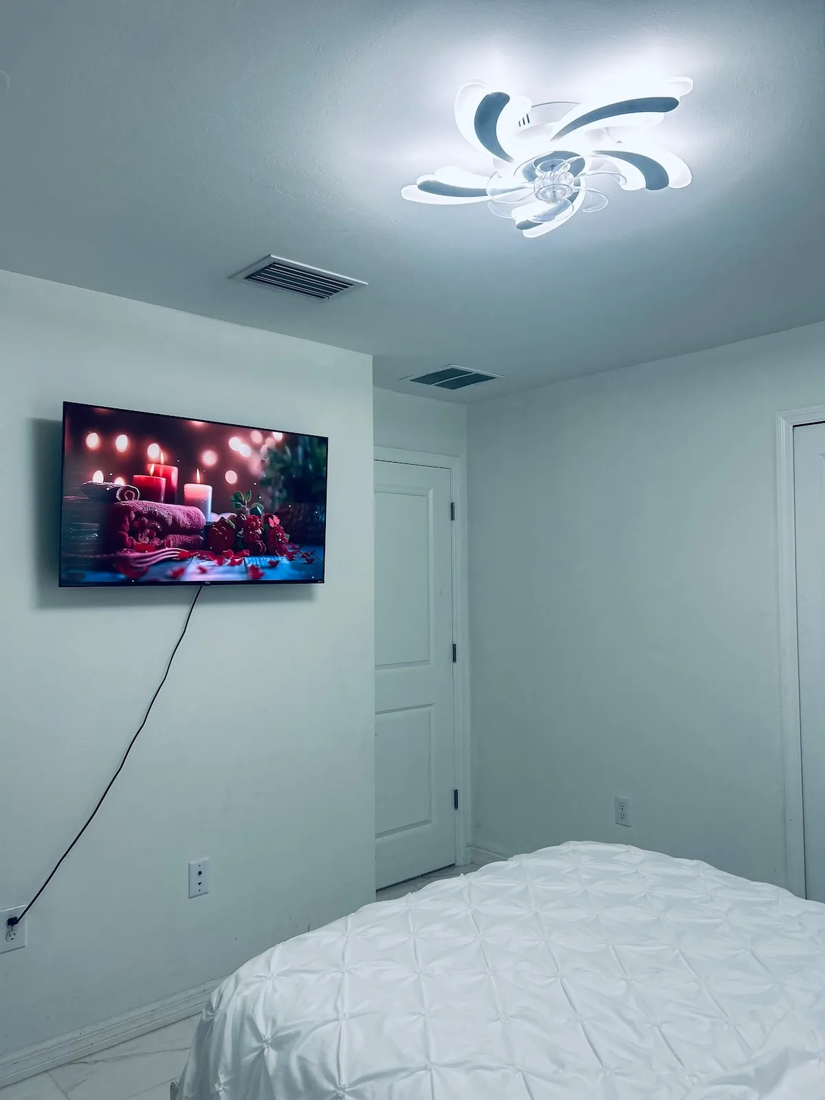 A bedroom with a bed and a wall-mounted television.