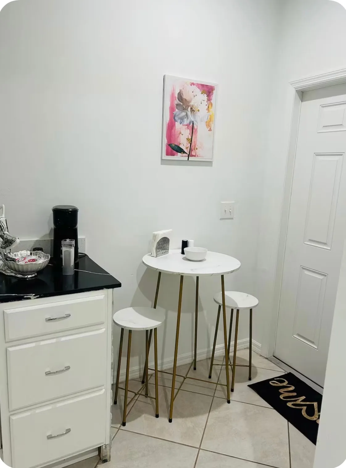 A small dining nook has a round table and stools beside a kitchen counter.