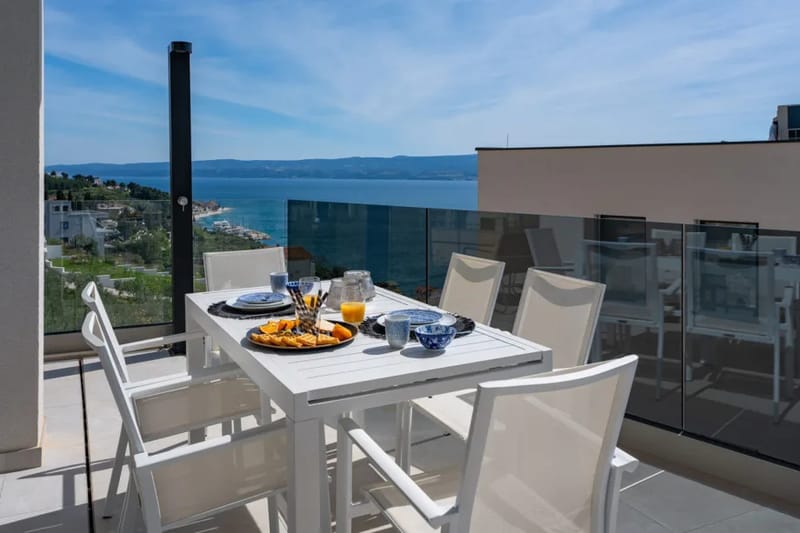 Mesa de comedor exterior bajo cubierta con vistas al mar