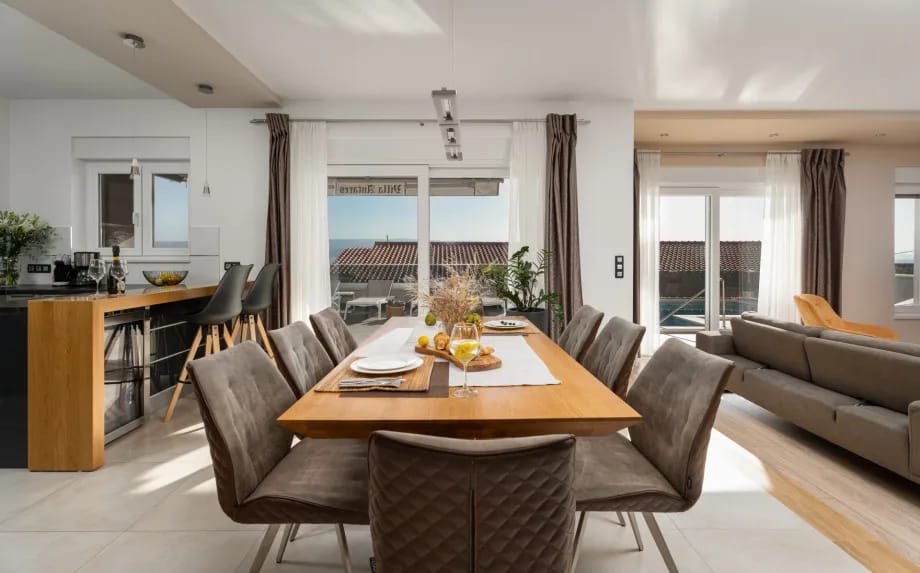 Mesa de comedor para 8 personas y cocina totalmente equipada conectada con la zona de la piscina