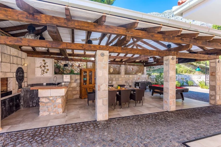 Zona de comedor exterior cubierta con barbacoa y billar