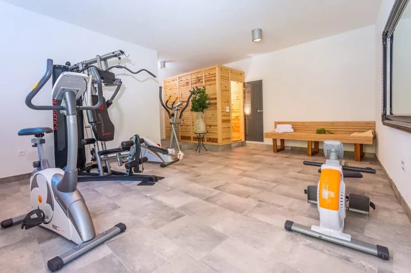 Sauna finlandesa, aire acondicionado y equipamiento para entrenar, unos escalones más abajo de la zona de la piscina
