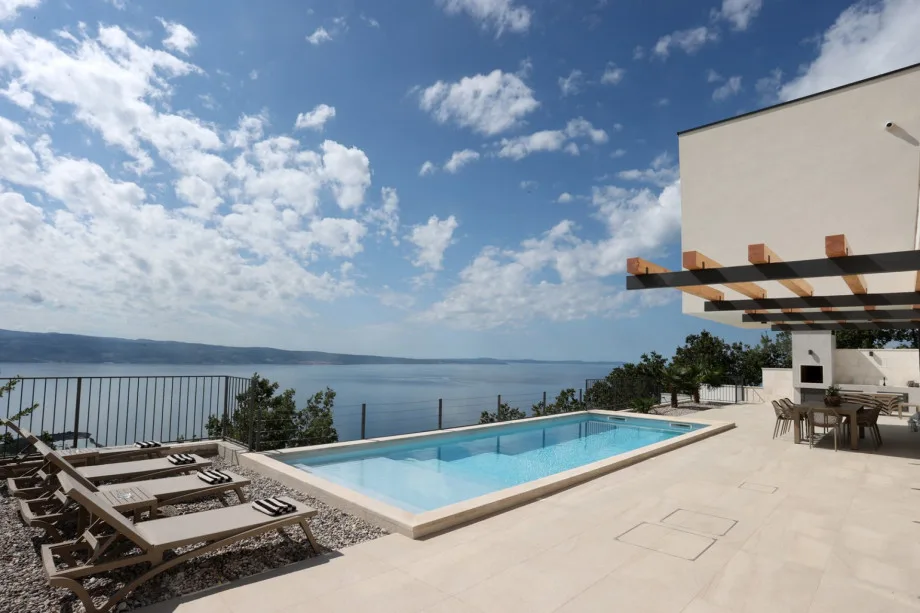 Relájese en la terraza para tomar el sol junto a la piscina de 33 m² mientras disfruta de vistas panorámicas al mar.