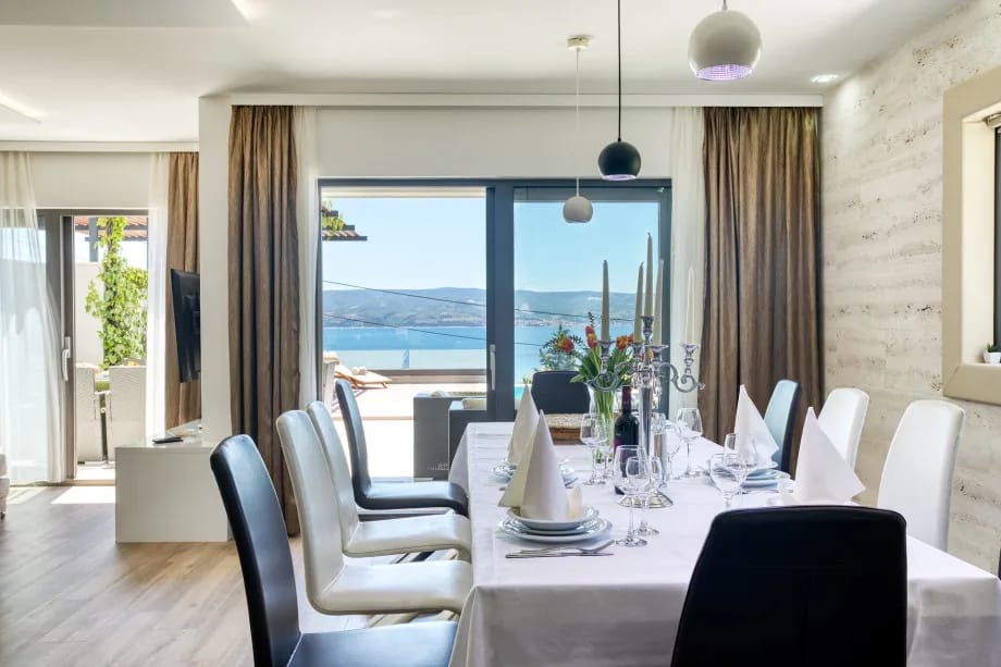 Zona de comedor para 12 personas con vistas despejadas a la piscina y al mar