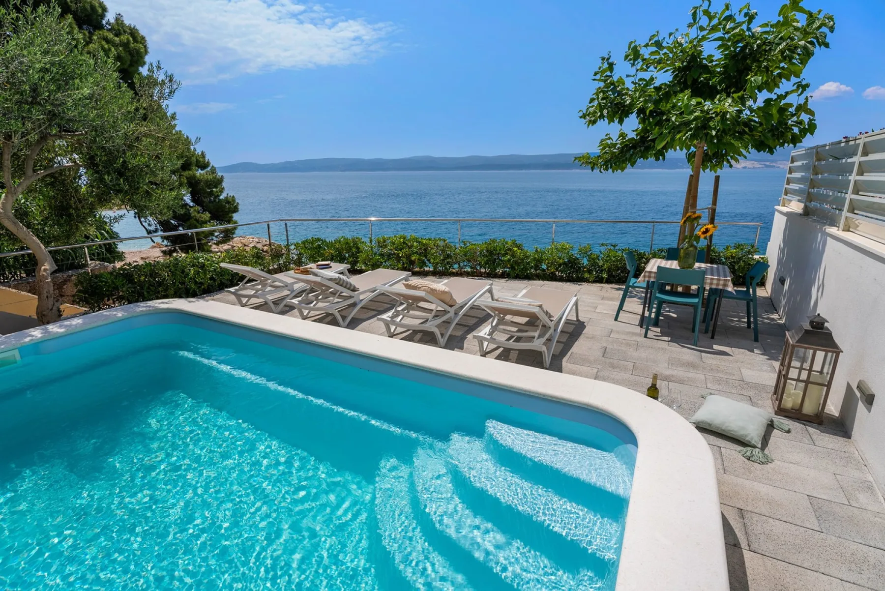 A swimming pool and loungers overlook the sea.