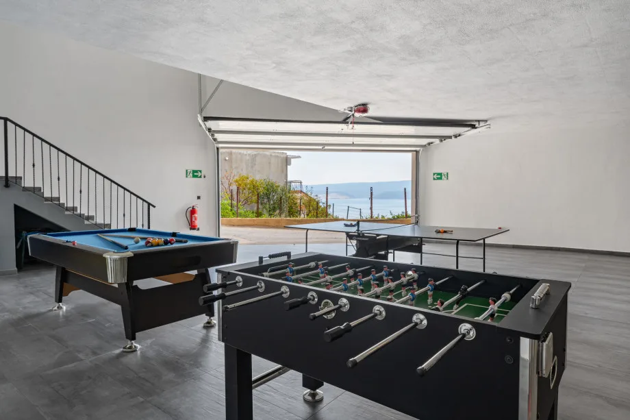 Zona de juegos con mesa de billar, mesa de ping-pong y futbolín en el garaje