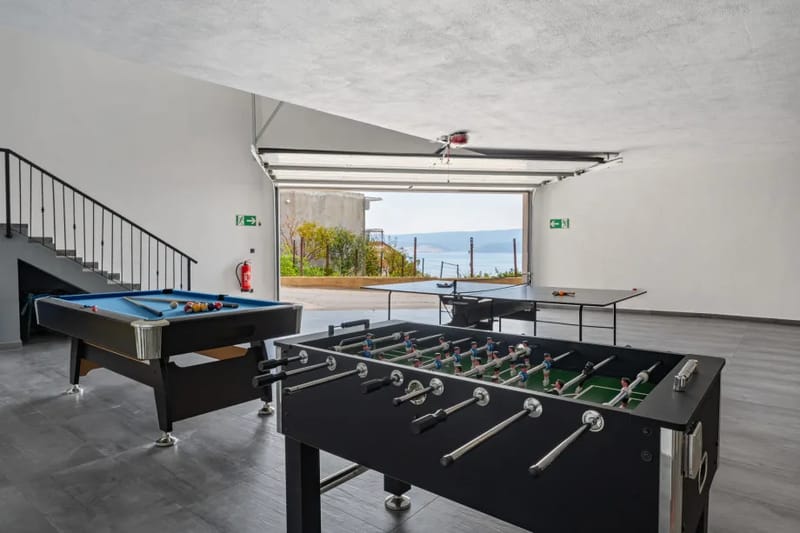 Zona de juegos con mesa de billar, mesa de ping-pong y futbolín en el garaje