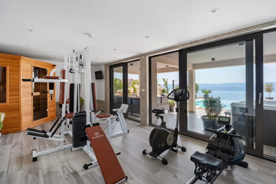 Sauna y gimnasio con aparatos de ejercicio al nivel de la piscina