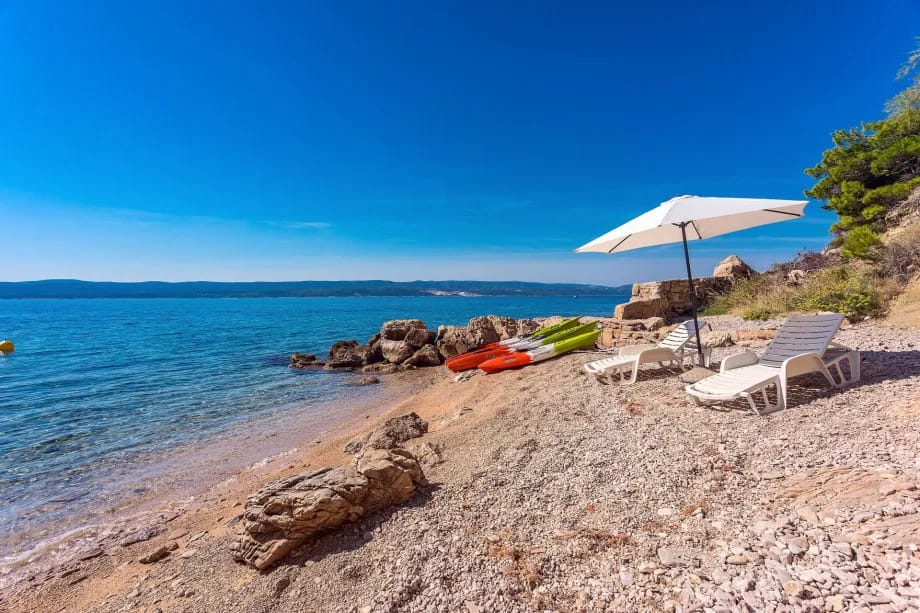 Private beach with beach chairs, parasol and shower