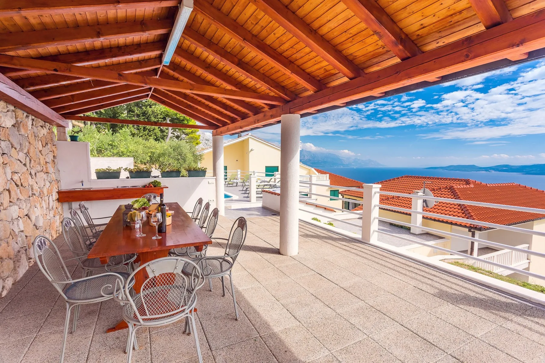Comedor exterior cubierto con una mesa larga y vistas al mar.