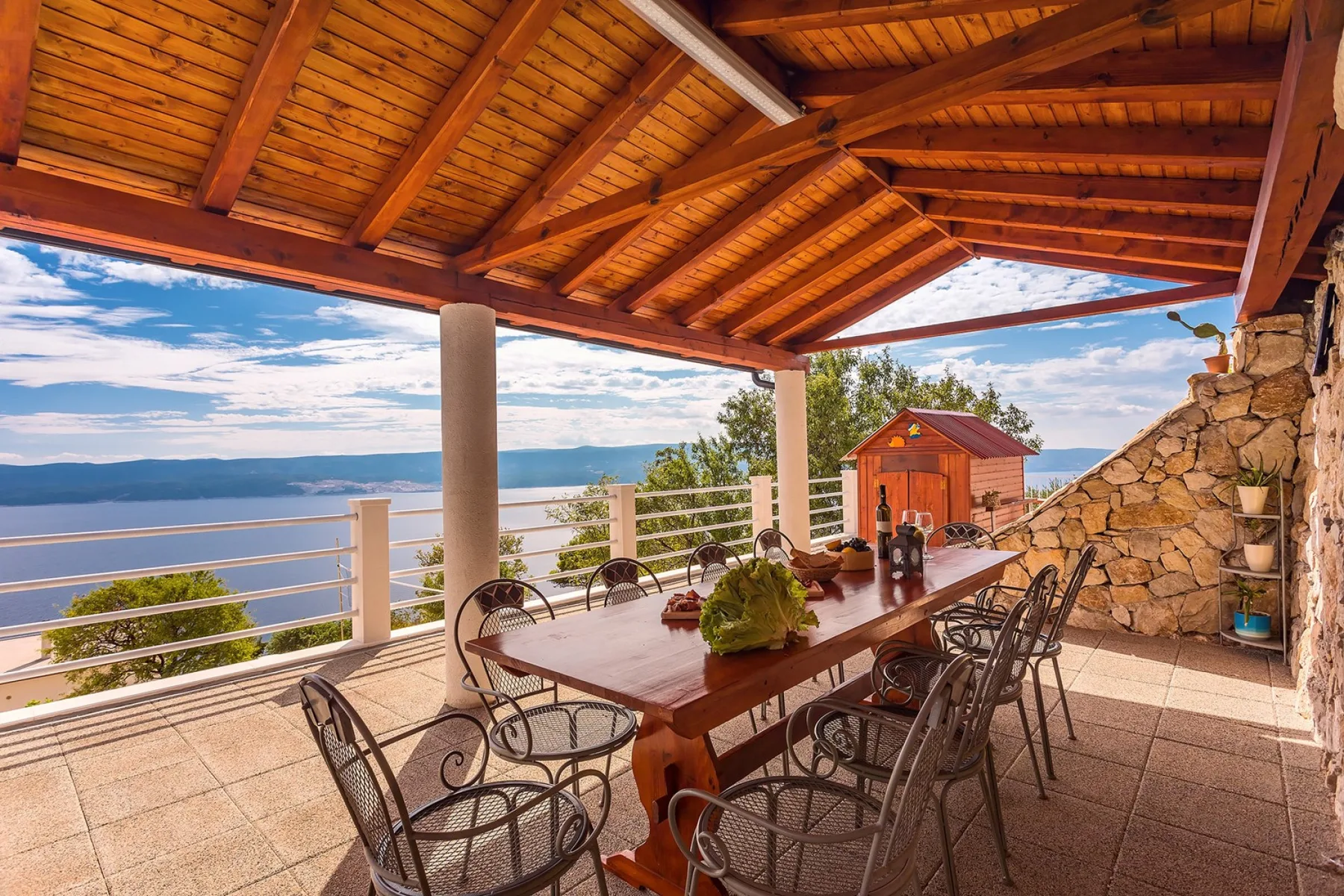 Covered outdoor dining area with a long table overlooking the water.