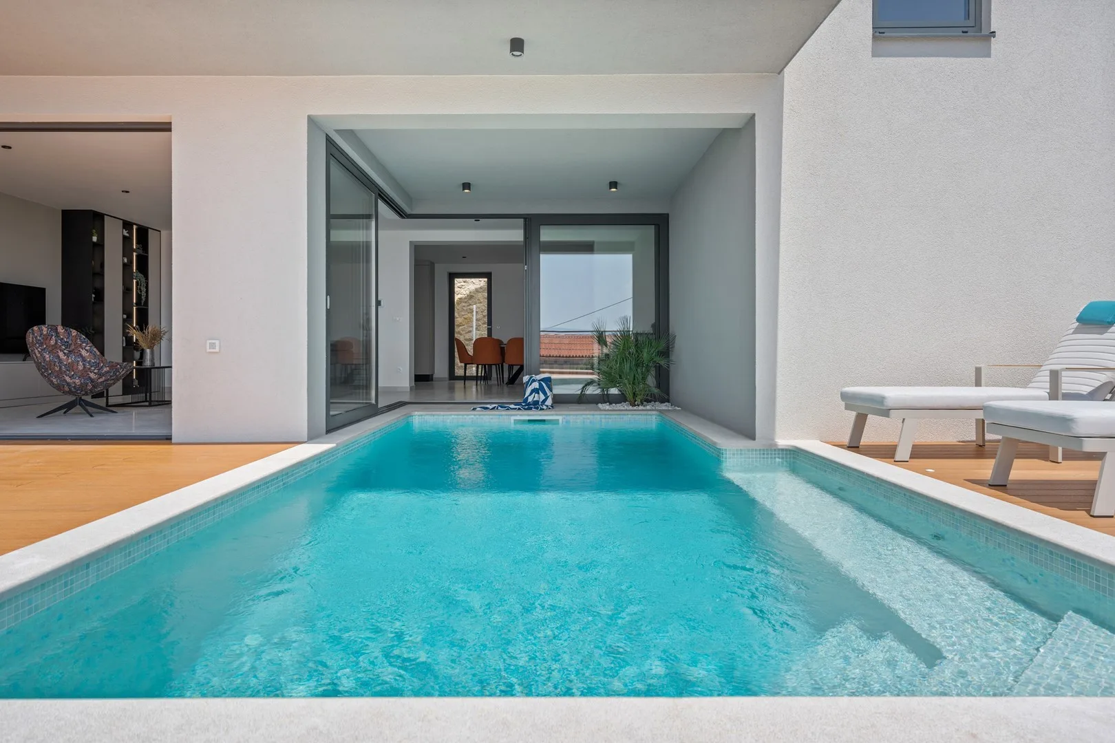 A rectangular swimming pool extends toward a covered seating area.