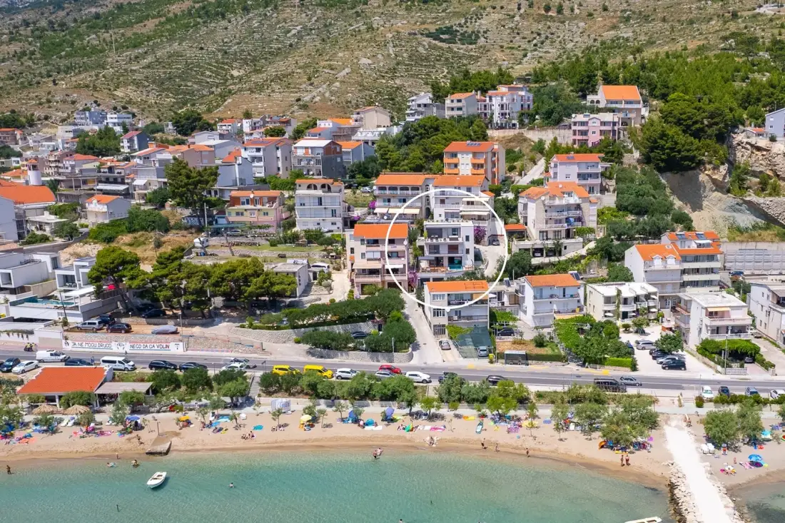 Aerial view of a coastal town, with a beach and buildings along the shoreline.