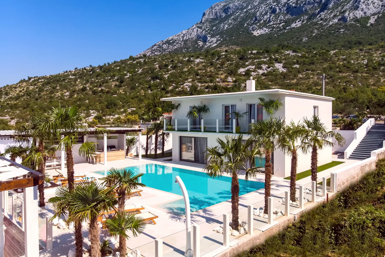 Una villa moderna se asoma a una piscina rodeada de palmeras.