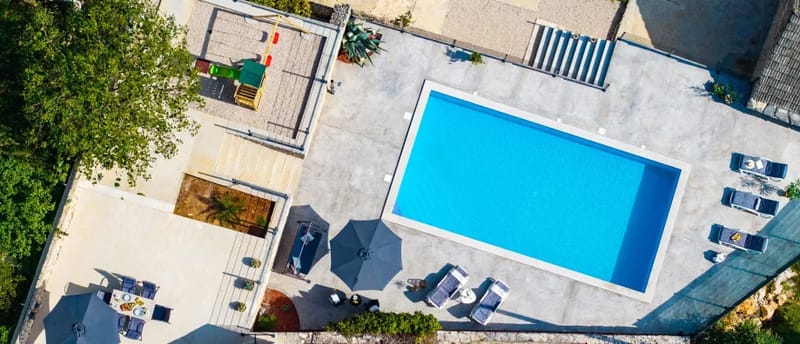 Una vista aérea de la piscina privada y de la zona exterior, incluida la zona de juegos infantiles.