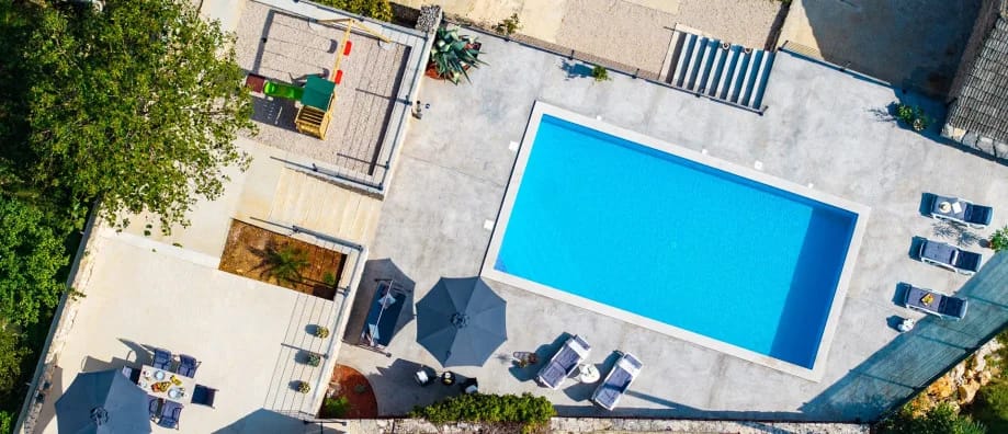 Una vista aérea de la piscina privada y de la zona exterior, incluida la zona de juegos infantiles.