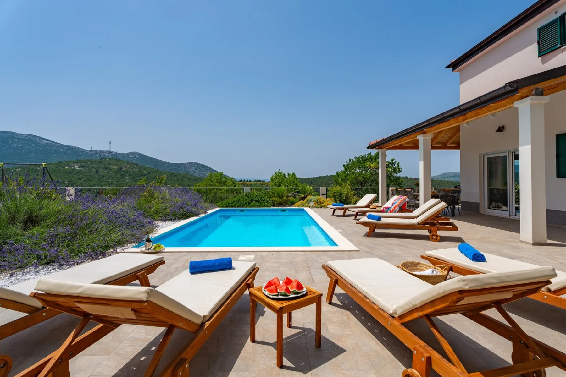 Una piscina exterior está junto a una terraza con tumbonas reclinables.
