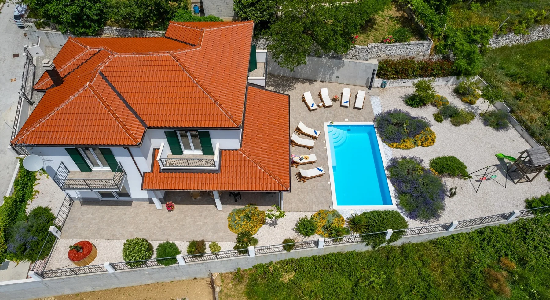 Una casa y una piscina al aire libre están rodeadas de zonas ajardinadas.
