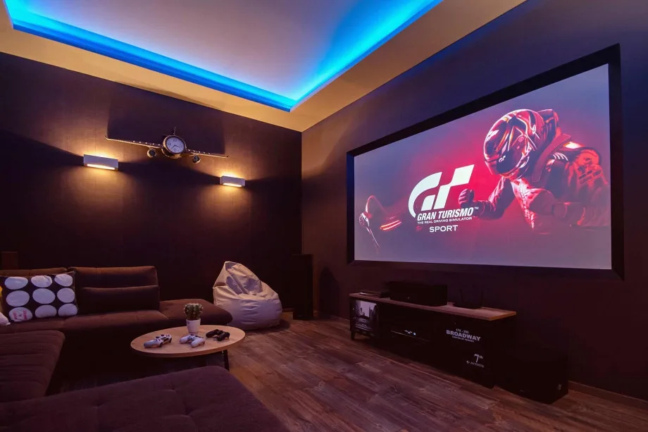 Sala de cine con un sofá enorme, pufs, aire acondicionado, wifi gratuito, PS4, Netflix y más