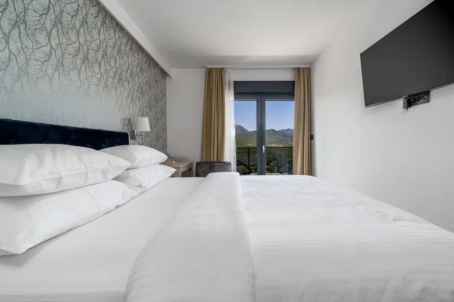 Dormitorio 1 con cama queen, sofá cama, baño privado integrado, televisor, aire acondicionado y balcón