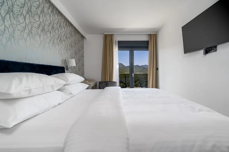 Dormitorio 1 con cama queen, sofá cama, baño privado integrado, televisor, aire acondicionado y balcón