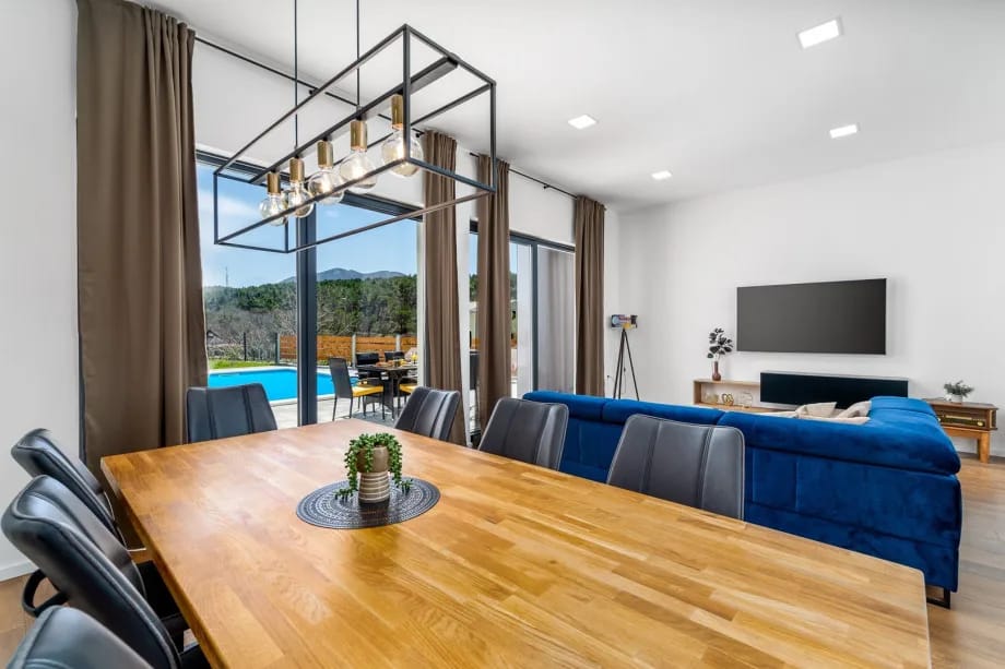 Zona de comedor y sala de estar con puertas correderas de cristal hacia la zona de la piscina