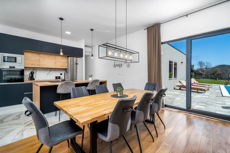 Open-plan kitchen and dining area with sliding glass doors toward the pool area