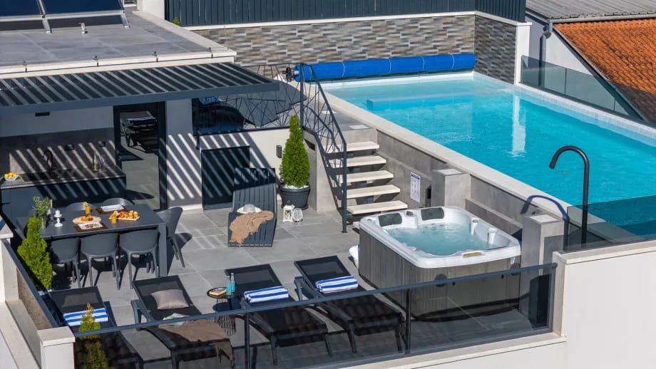 Rooftop terrace with a heated pool, whirlpool, lounge chairs, and outdoor shower