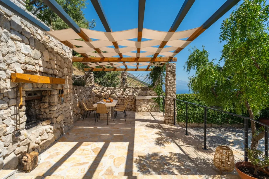 Covered outdoor dining area with stone table and traditional barbecue
