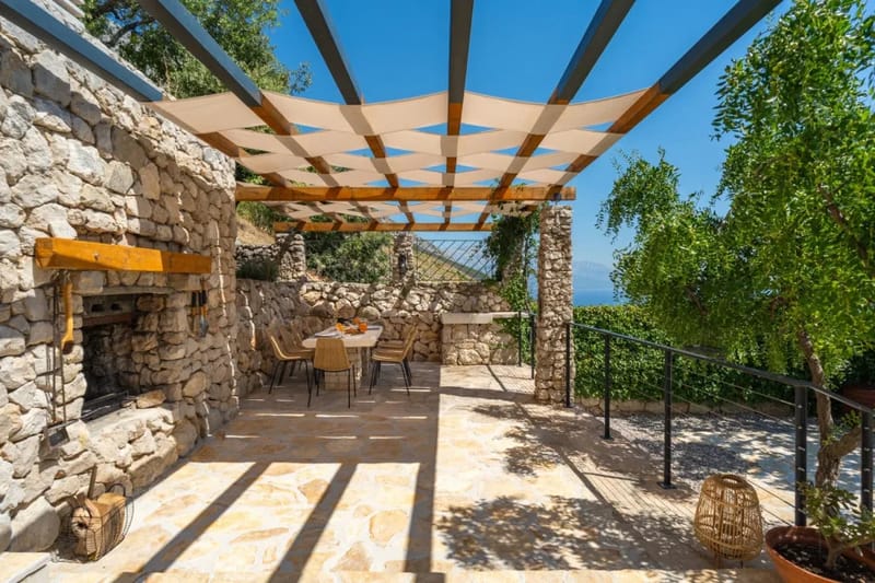 Covered outdoor dining area with stone table and traditional barbecue