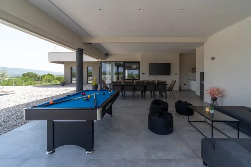 Zona cubierta (77 m²) con una cocina exterior, una barbacoa tradicional (leña y carbón), un televisor enorme de pantalla plana con altavoces de sonido envolvente y una mesa de comedor para 12 personas