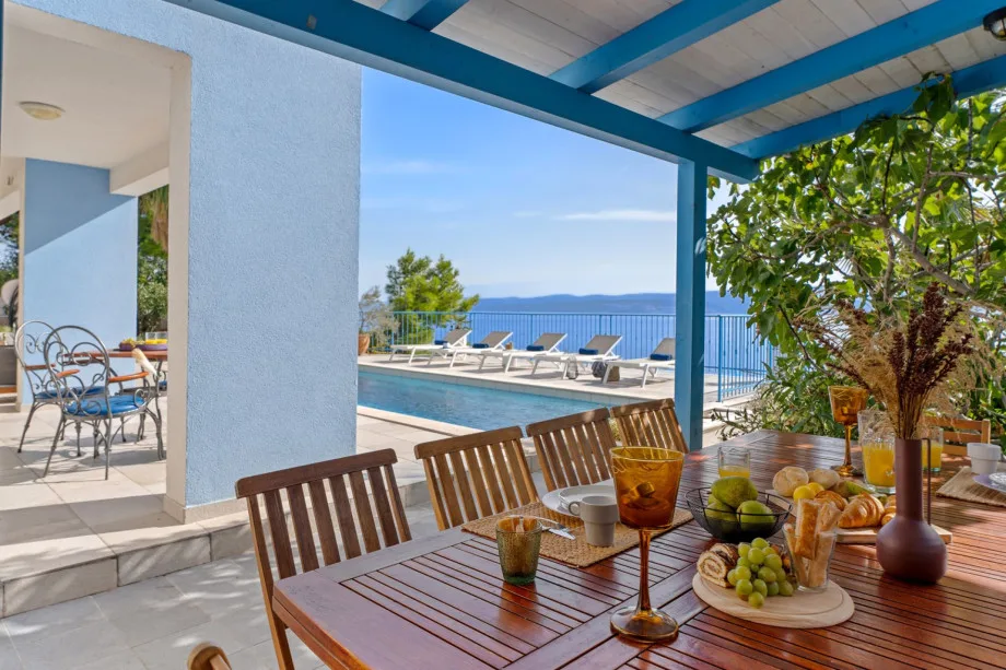 Covered outdoor dining area with traditional barbecue, and a lounge area