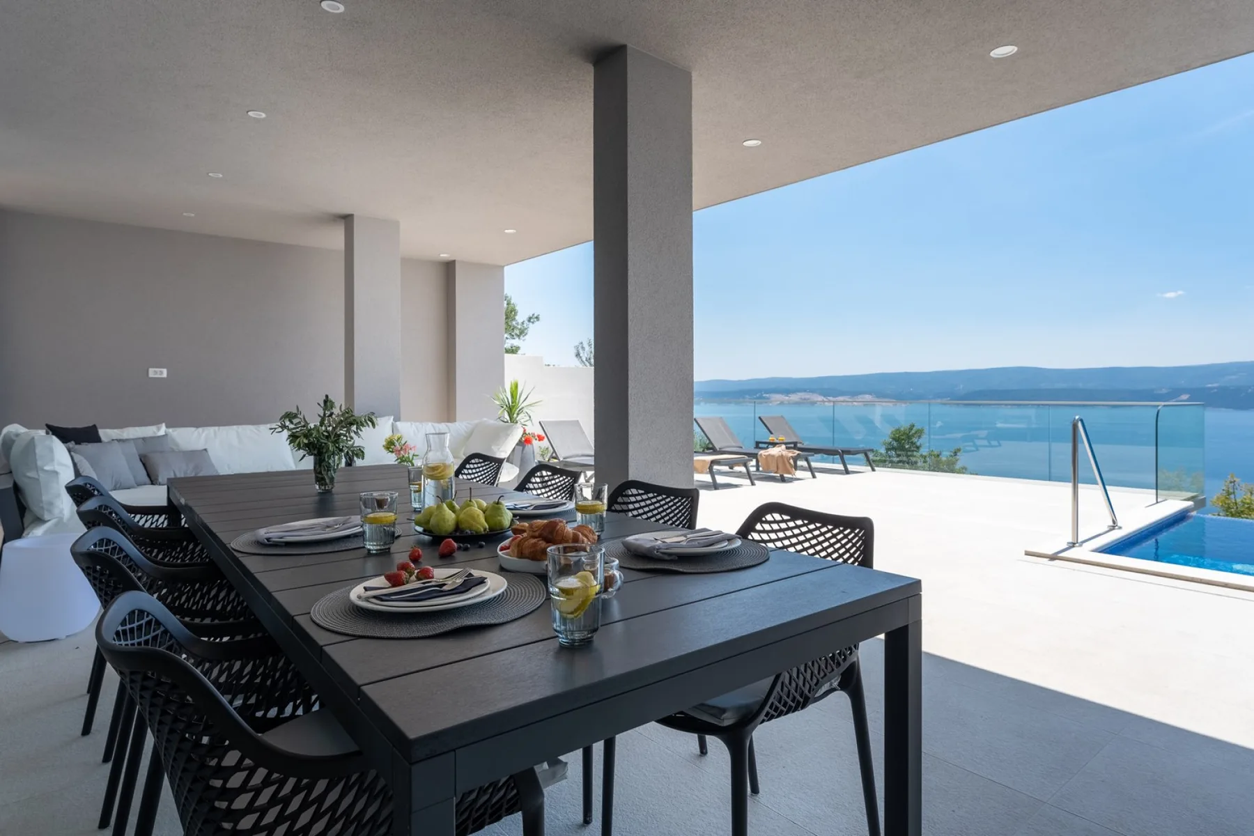 Zona de estar de planta abierta con zona de comedor exterior cubierta, barbacoa y rincón de descanso