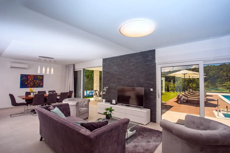 A living room with TV, and exit to a pool and outdoor dining area.